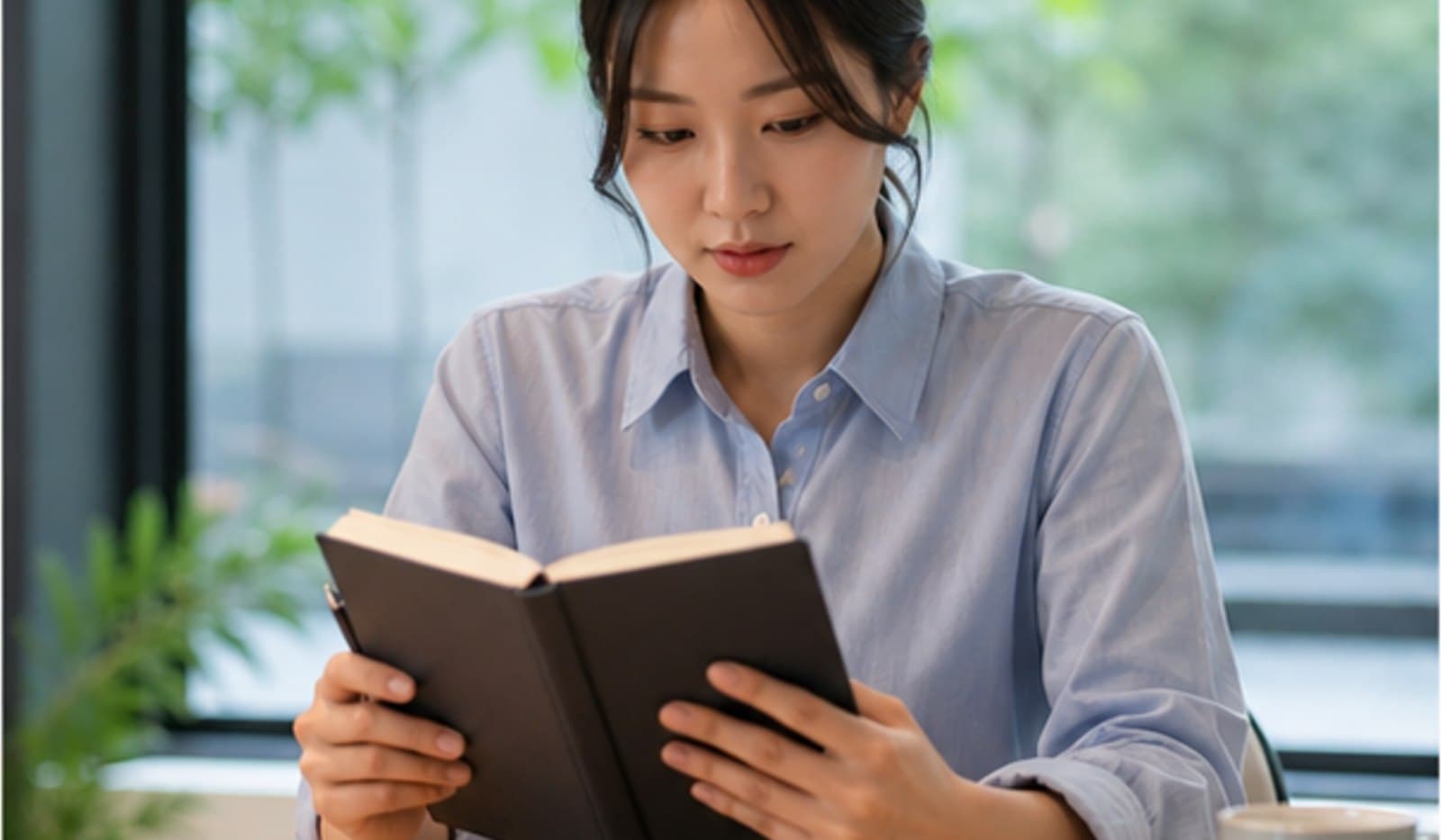 창가에서 자료를 읽으며 안과 방문을 준비하는 모습
