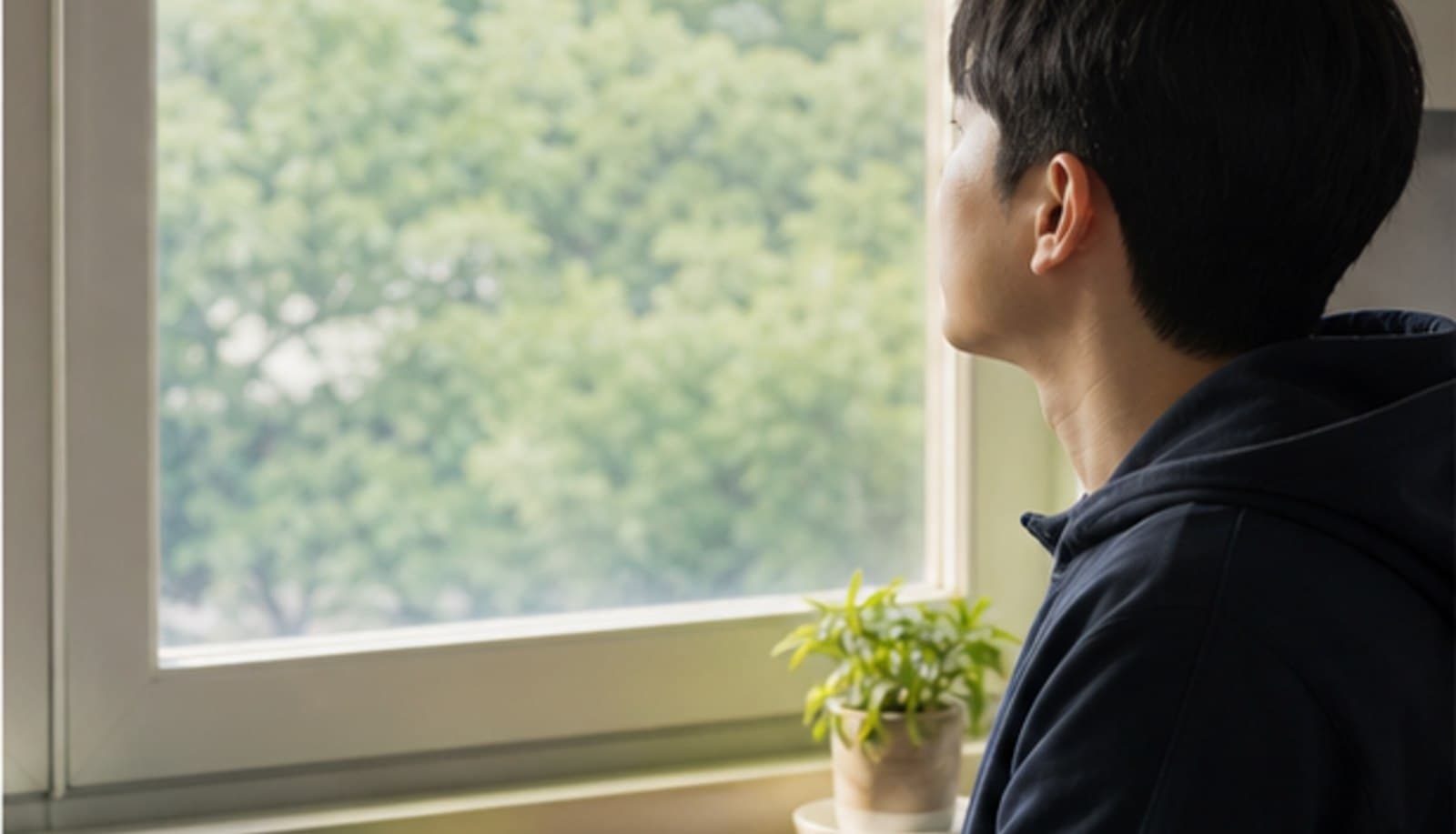창가에서 바깥 나무를 바라보며 화면에서 눈을 떼고 쉬는 모습