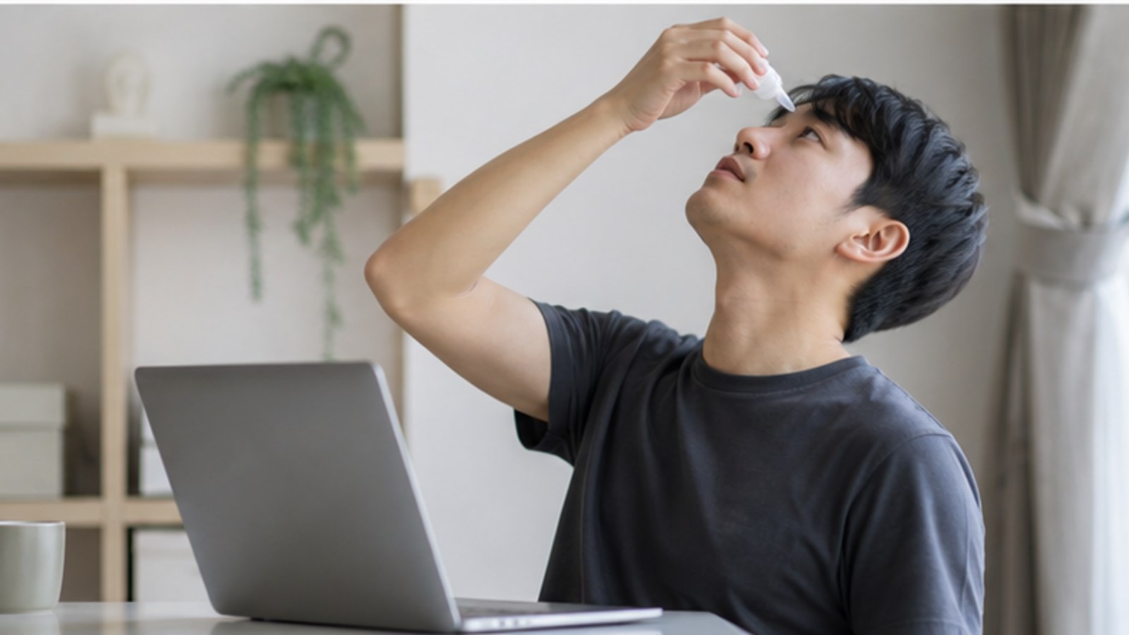 책상에서 처방받은 안약을 사용하는 사람