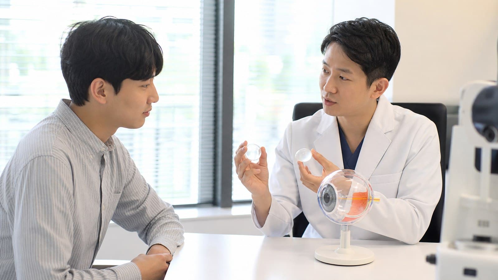 밝은 진료실에서 의료진이 각막 모형을 들고 내원자에게 여러 시력교정 방향을 설명하는 상담 장면
