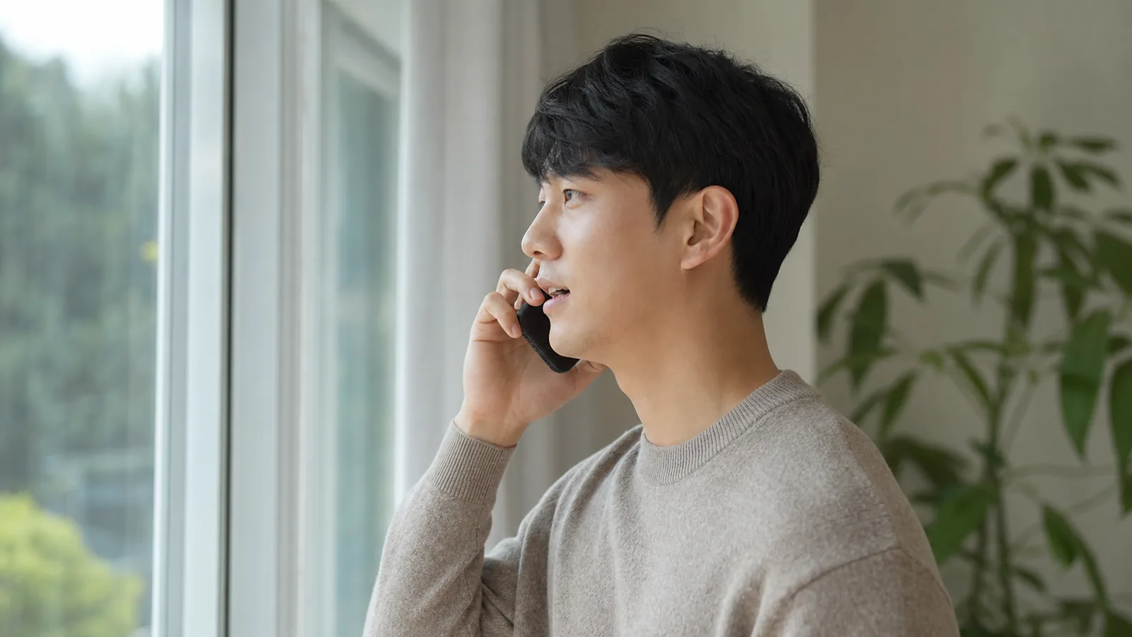 창가에서 바뀐 사정을 전화로 알리는 성인의 모습